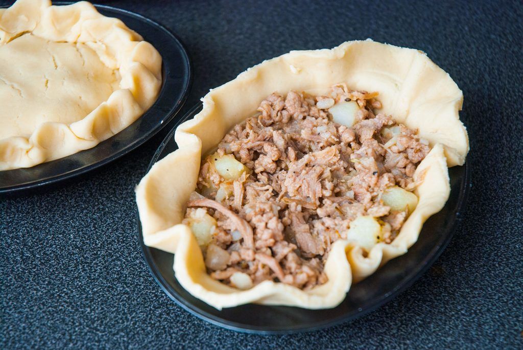 Shortcrust pastry lined in a mini pie tin, filled with pork and potato mixture.
