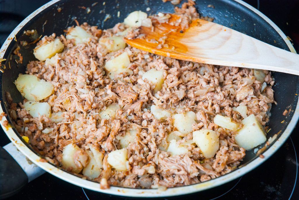 Pork mince, shredded roast pork and cooked potato frying in a pan.