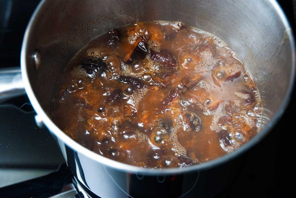 Prunes simmering in water in a saucepan.