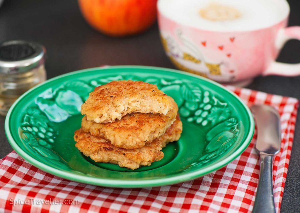 Three stacked Croatian apple fritters, top one with a bite taken out to reveal soft interior with apple and oats.
