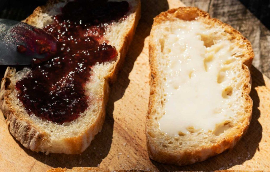Rustic bread slices with butter and French prune jam served for breakfast.
