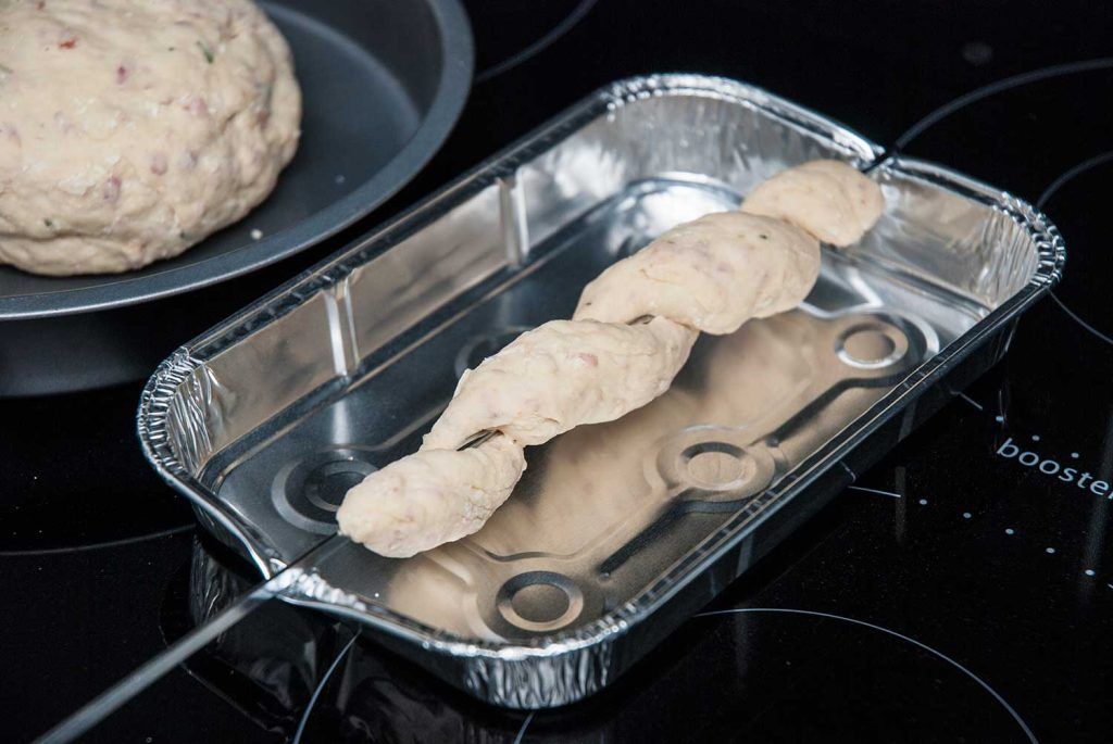 Damper bread dough wrapped around a BBQ stick ready to bake.
